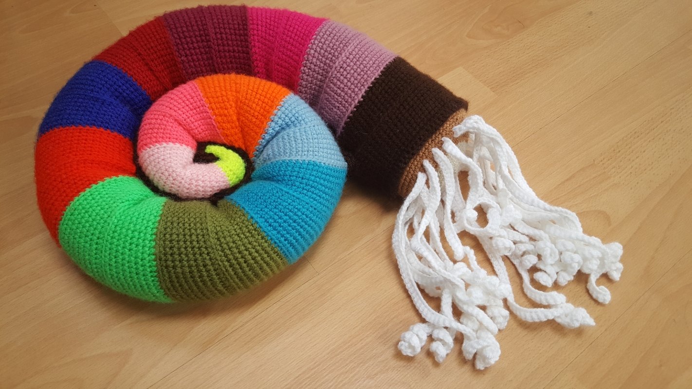 Buntes gehäkeltes rundes Kissen mit gestreifter Spirale und weißen Quasten