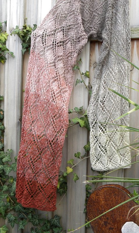 Zwei gestrickte Lacetücher mit Rautenmuster und Farbverlauf an einem Holzzaun