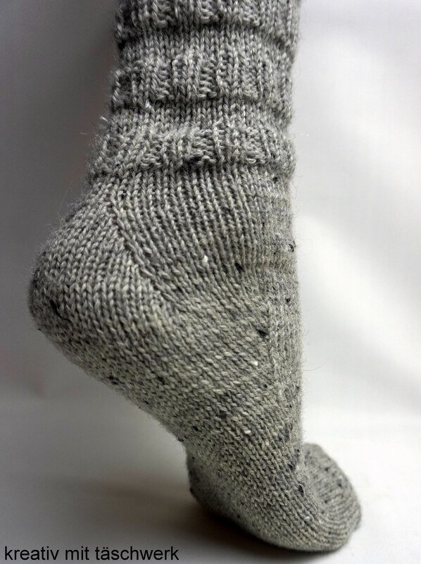 Gestrickte graue Socke mit Rippenbündchen; Detailansicht von Ferse und Schaft.