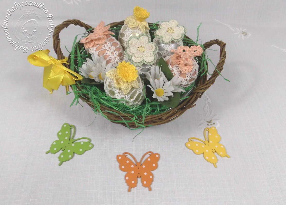 Weidenkörbchen mit gehäkelten Eierhüllen, Häkelblüten, Gänseblümchen und Papier-Schmetterlingen