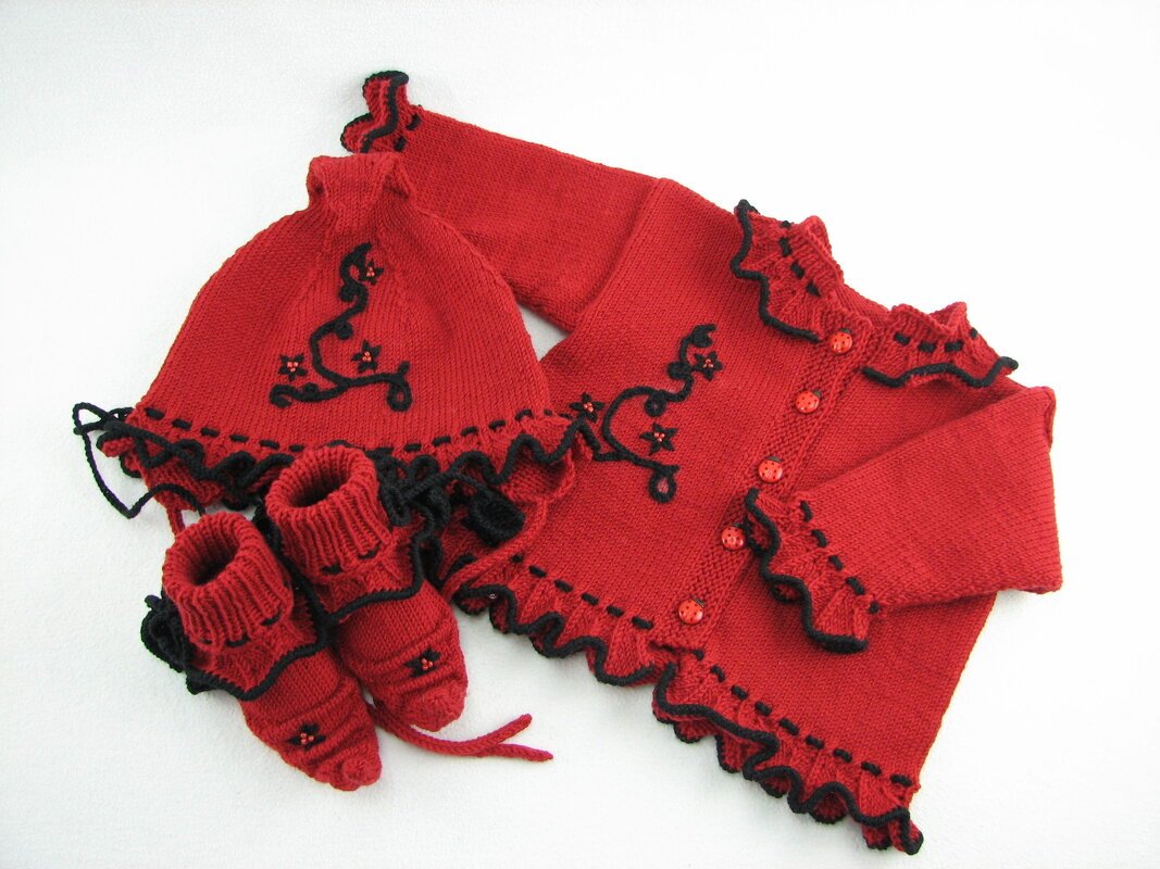 Gestricktes Baby-Set in Rot mit schwarzer Rüsche: Jacke, Mütze und Schühchen.