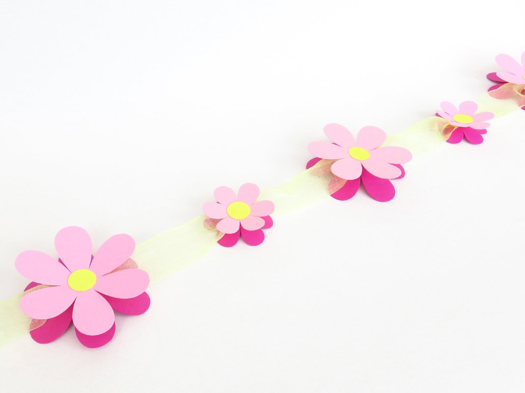 Girlande aus rosa Papierblumen auf hellem Band