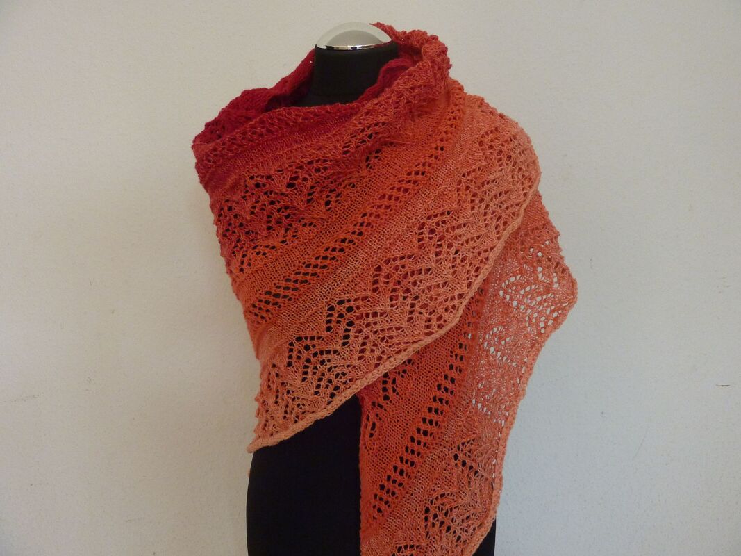 Rot‑oranges Lacetuch mit Farbverlauf und feinem Lochmuster auf schwarzer Schneiderpuppe