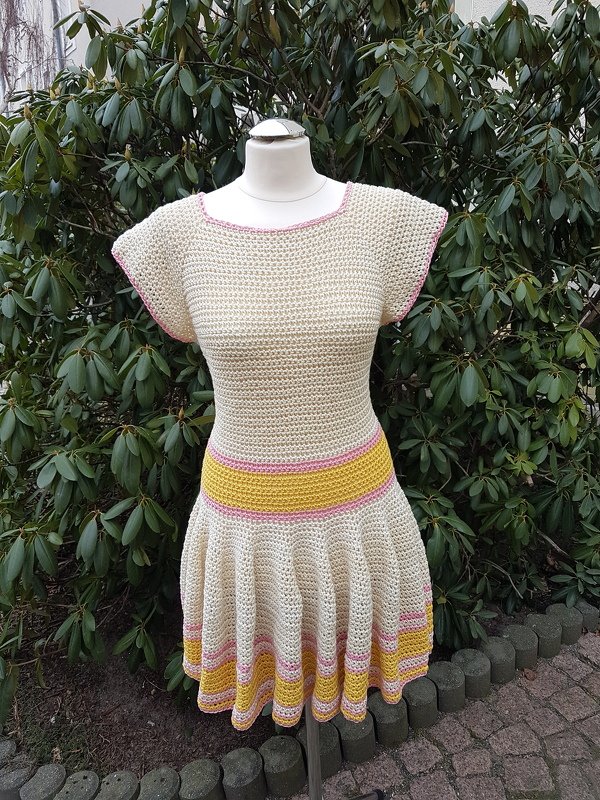 Schaufensterpuppe mit gehäkeltem cremefarbenem Kleid, gelbe und rosa Streifen, ausgestellter Rock