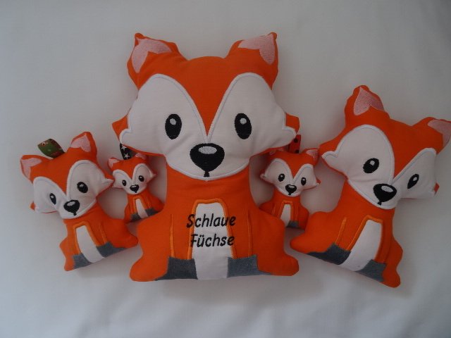 Fünf bestickte Fuchs-Stofffiguren in Orange; größte Figur mit Schriftzug ‚Schlaue Füchse‘