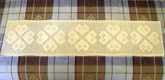 romantischer cremefarbener Häkel-Tischläufer mit Herzornamenten auf kariertem Stoff