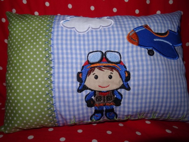 Kissen mit Stickmotiv Pilot, Flugzeug und Wolke auf blau-weiß kariertem Stoff und grüner Pünktchenborte