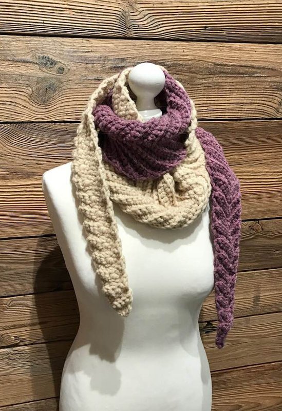 Gehäkelter Schal in Beige und Lila mit Zopfmuster auf weißer Schaufensterpuppe vor Holzwand