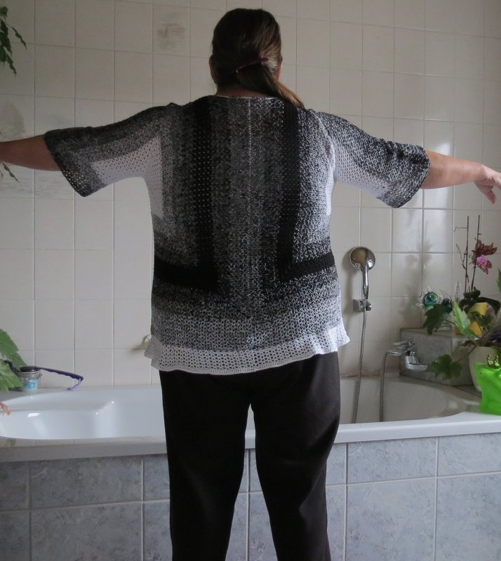 Rückansicht eines gehäkelten Damen‑Shirts mit Schwarz‑Grau‑Weißem Farbverlauf und kurzen Ärmeln.