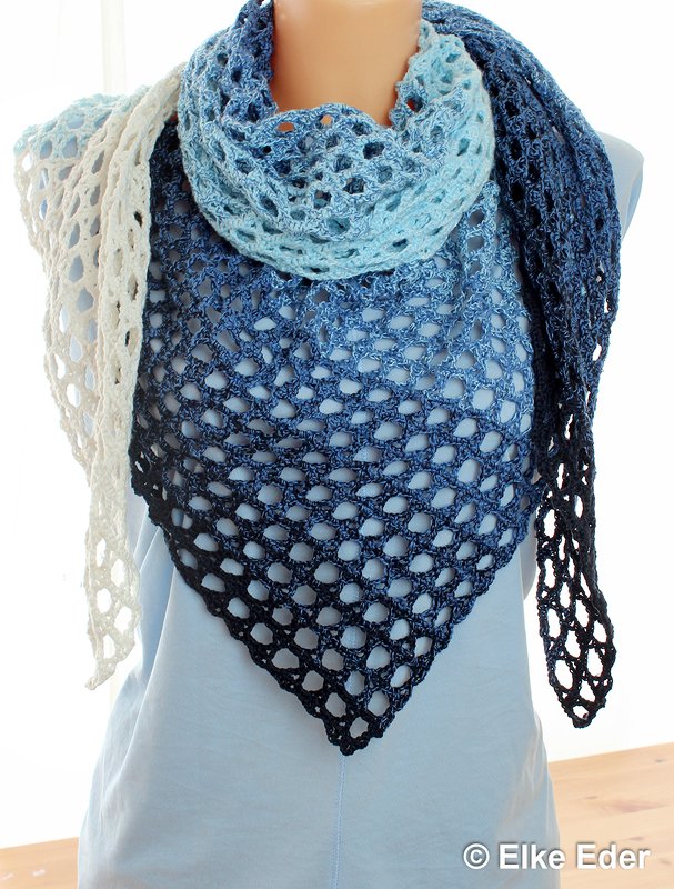 Crocheted ombre triangle shawl in white, light blue, and navy with openwork stitch pattern, draped on a mannequin.