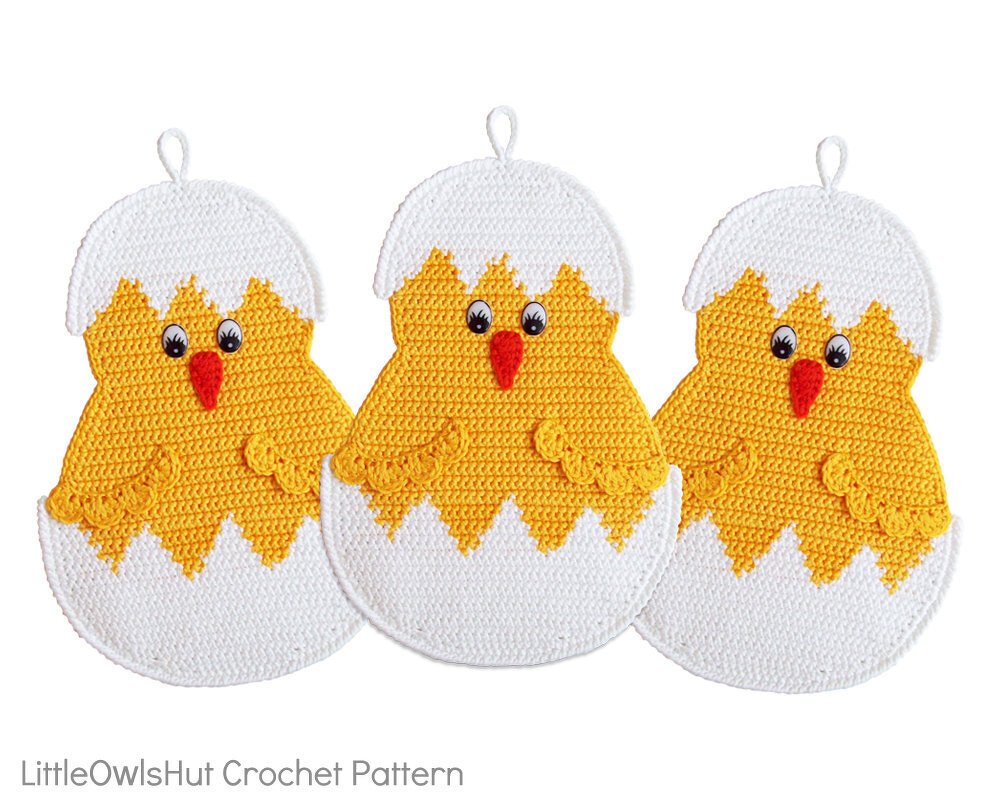 Three yellow crocheted chick potholders shaped like cracked white eggs with hanging loops