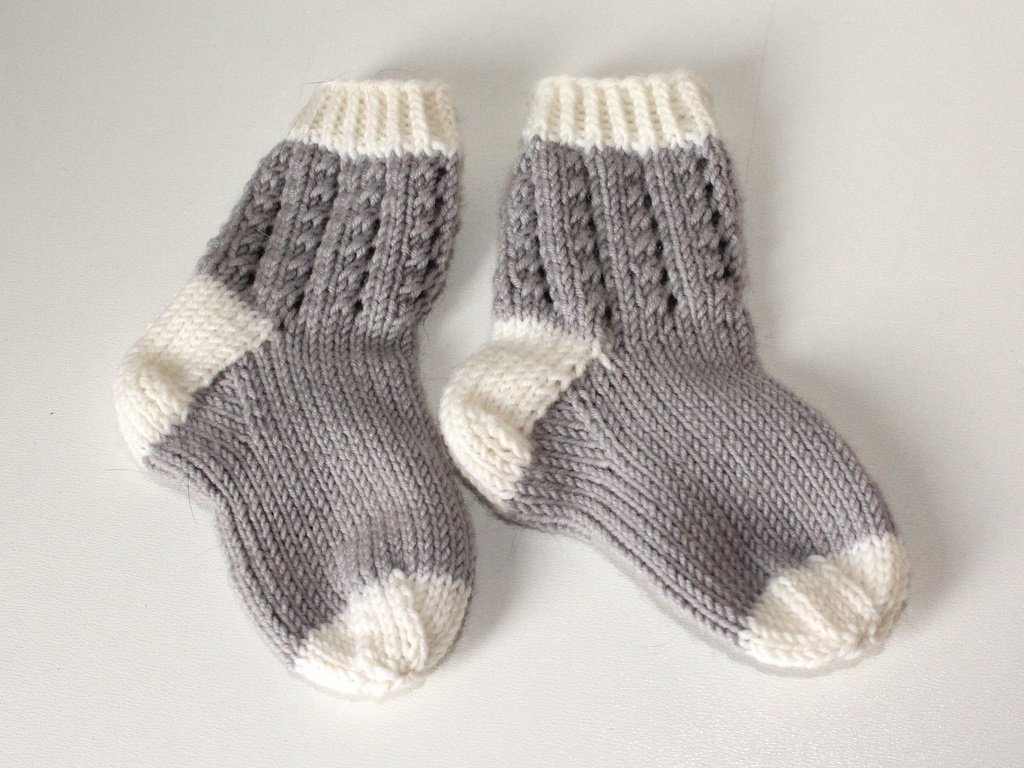 Paar gestrickter Babysocken grau-weiß mit Lochmuster am Schaft