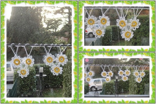 Reihe gehäkelter weißer Gänseblümchen mit gelben Mittelteilen an einer Schnur vor einem Fenster