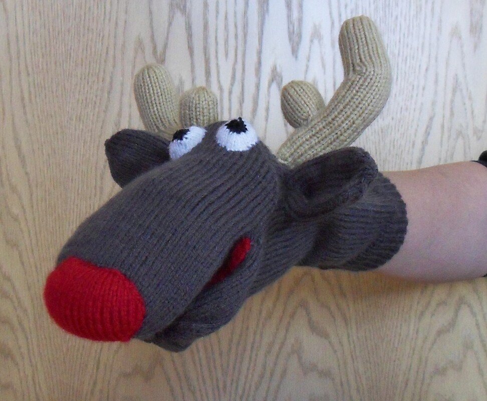 Gestrickte Rentier-Handpuppe mit roter Nase, weißen Augen und beigen Geweihen, Hand im Inneren