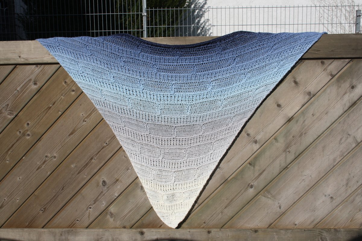 Gehäkeltes Dreieckstuch in Blau-Weiß an Holzzaun