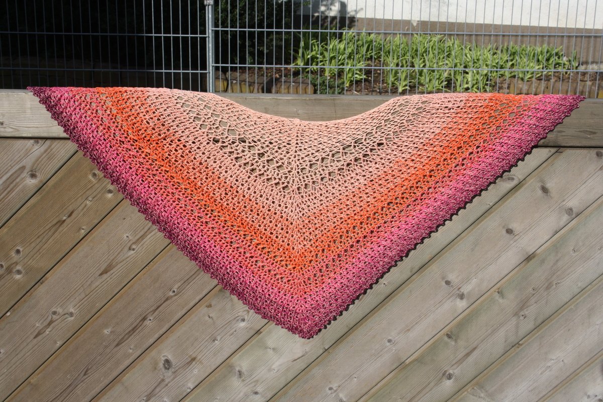 Gehäkeltes Dreieckstuch mit Farbverlauf von Beige über Orange bis Rosa, auf Holzlatte gespannt