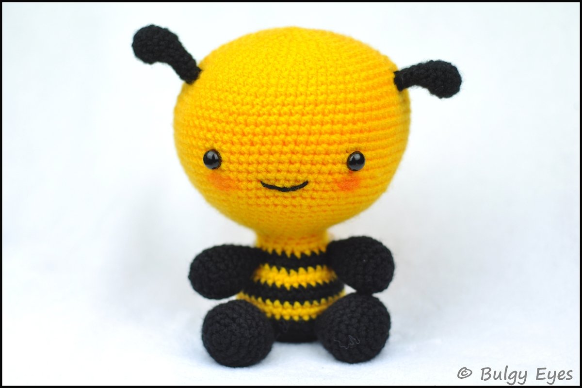 Gehäkelte gelb-schwarze Amigurumi-Biene mit lächelndem Gesicht