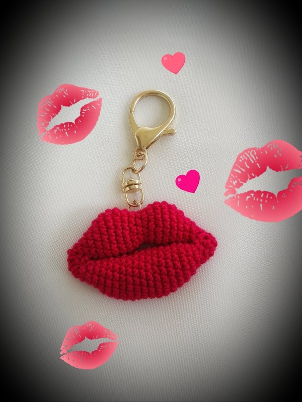 Roter gehäkelter Lippen‑Schlüsselanhänger mit goldfarbenem Karabiner auf hellem Untergrund
