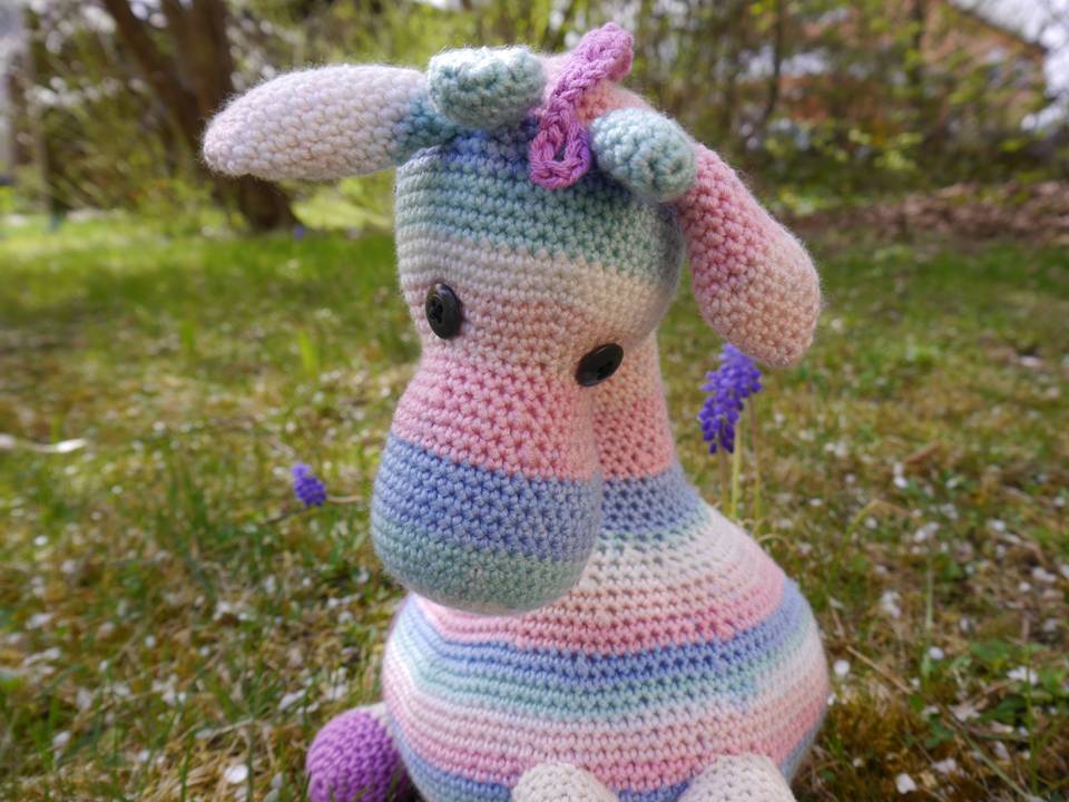 Nahaufnahme einer gehäkelten Giraffe: Maschenstruktur, Farbwechsel und Knopfaugen