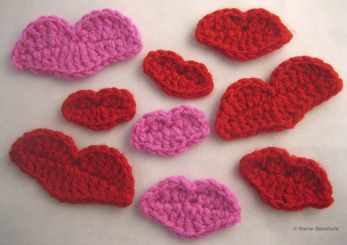 Rote und pinke gehäkelte Lippen und Herzen als Applikationen, Nahaufnahme