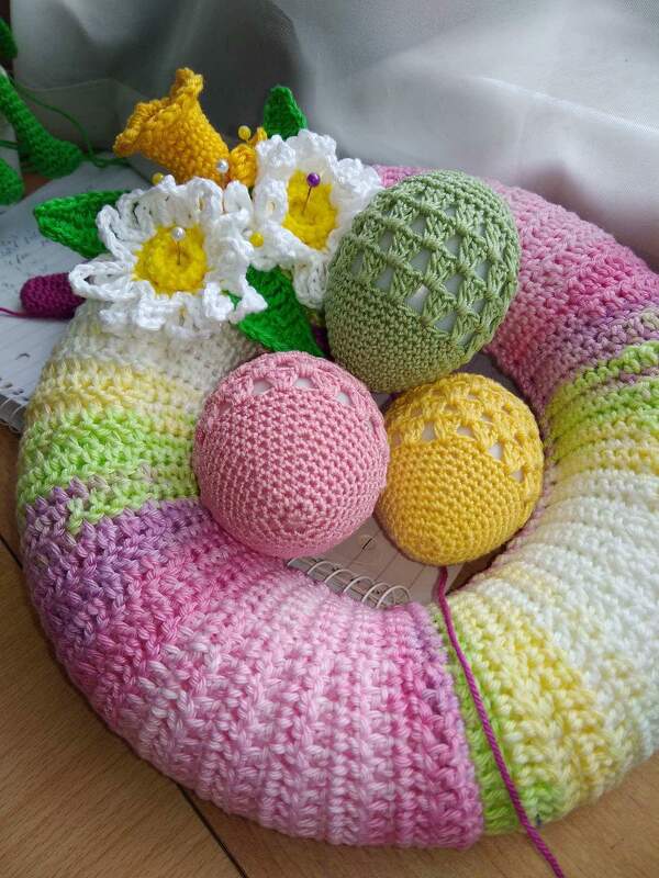 Gehäkelter Osterkranz in Pastellfarben mit Häkel-Eiern und Blüten.
