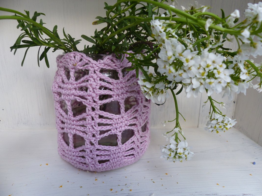 Glasvase mit pastellfarbener Häkelhülle und weißen Blüten