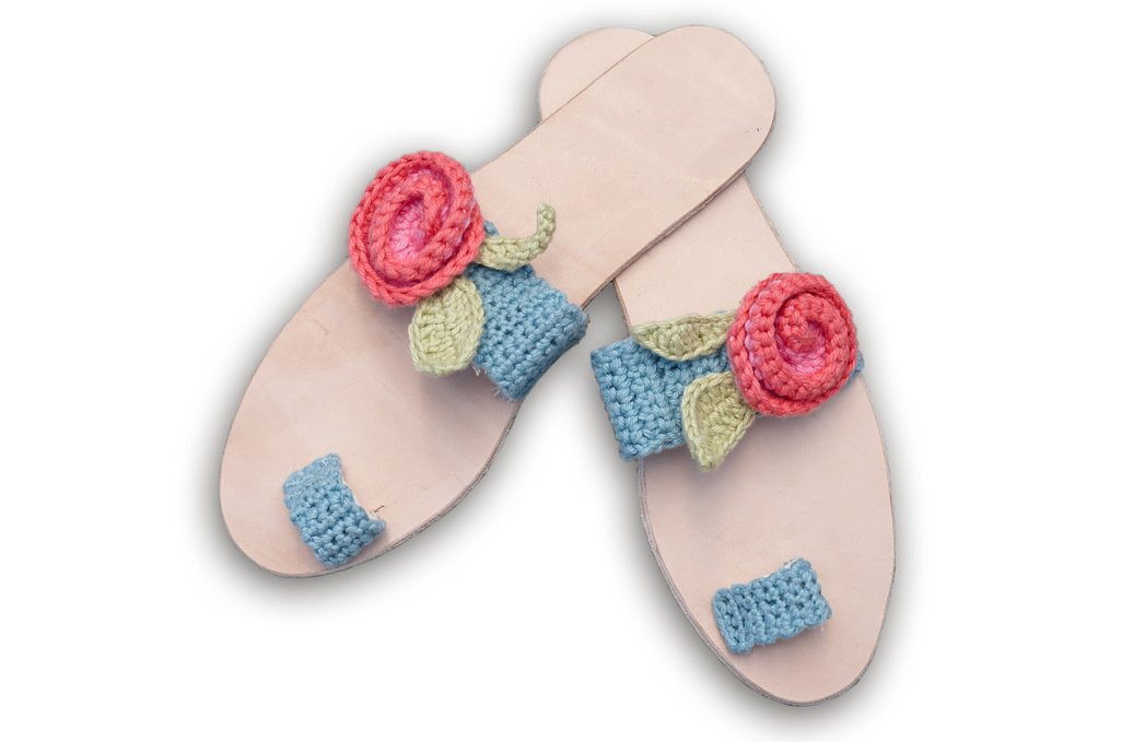 Paar flacher Sandalen mit pastellblauen Häkelriemen und rosafarbener Häkelblume