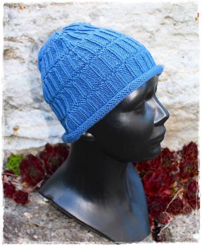Blaue gestrickte Beanie mit geometrischem Strukturmuster auf schwarzer Schaufensterbüste