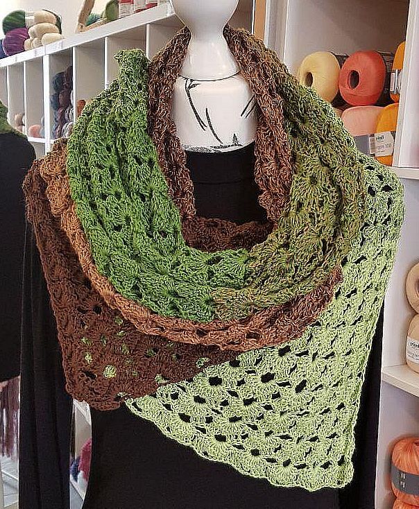 Großes gehäkeltes Dreieckstuch in Grün- und Brauntönen mit Muschelmuster als Loop-Schal auf einer weißen Schneiderpuppe