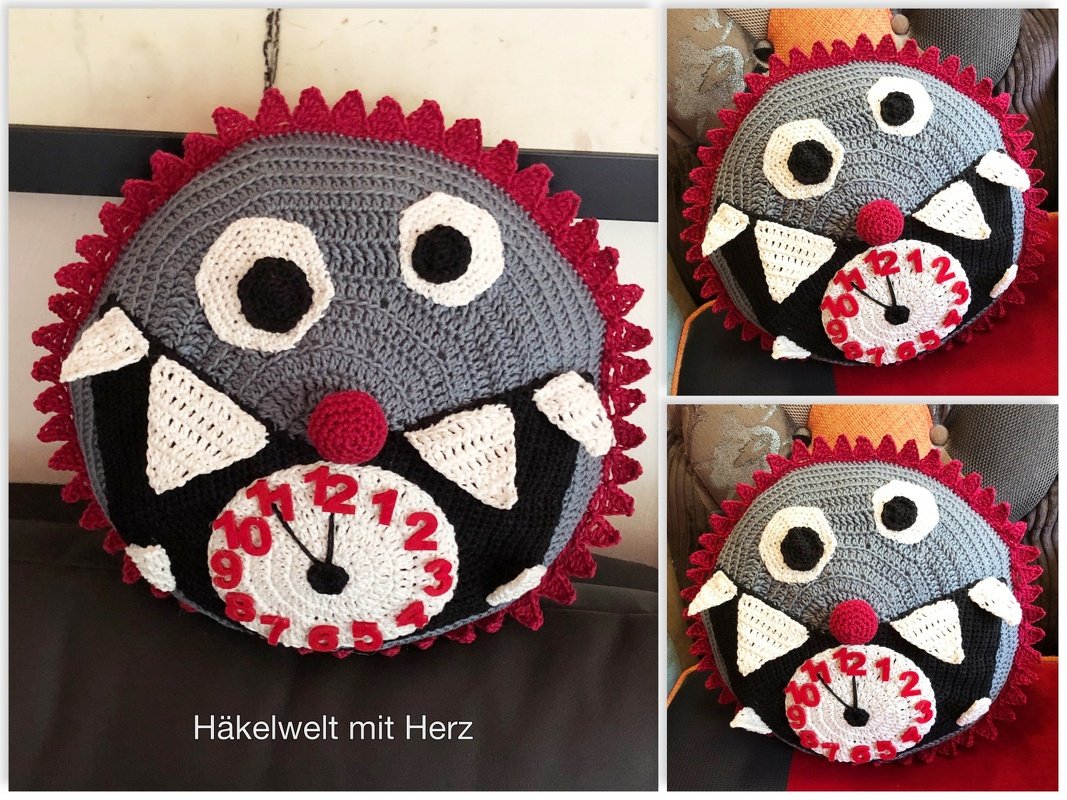 Rundes gehäkeltes Monsterkissen grau mit rotem Zackenrand, applizierten Augen, weißen Dreieckszähnen und zentraler Ziffern-Uhr