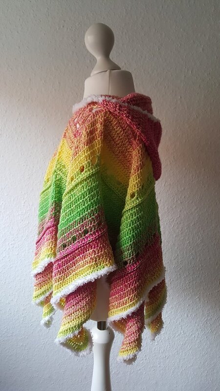 Gehäkelter Kinderponcho in Pastell-Regenbogenfarben mit Kapuze und weißem Saum auf Schneiderpuppe