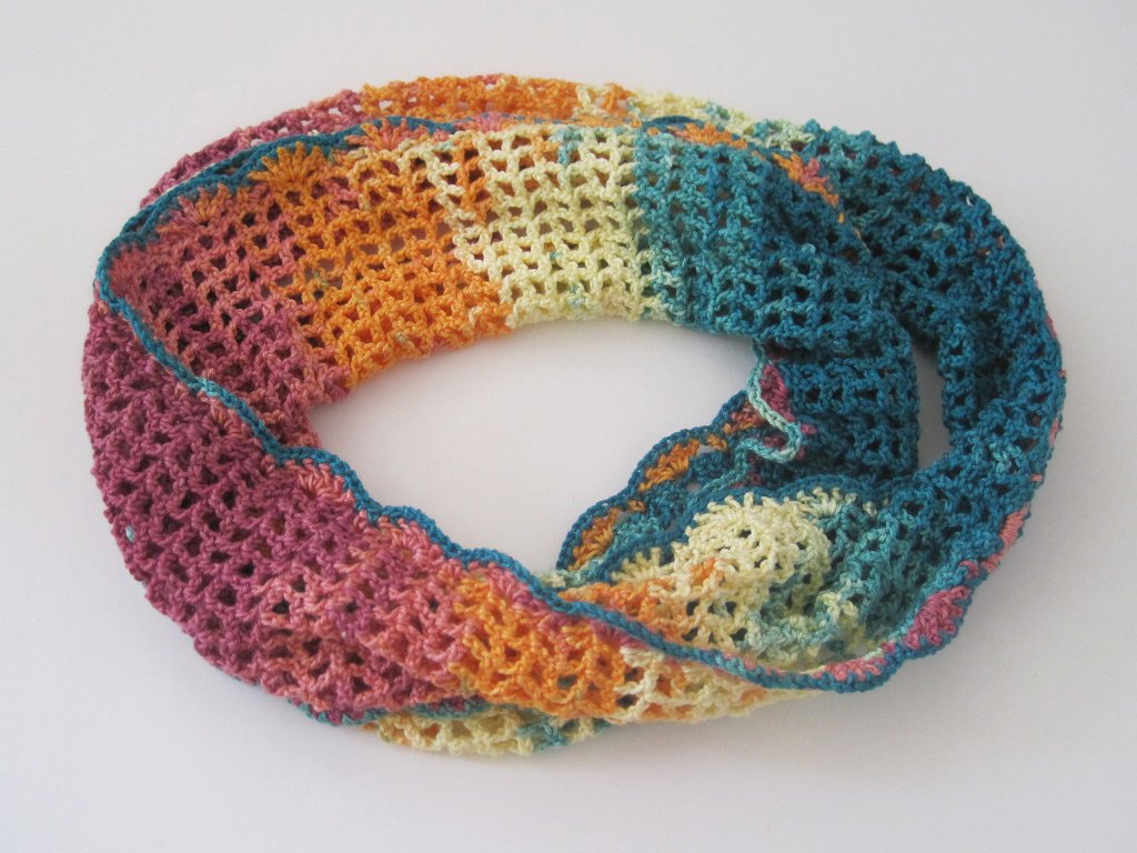 Gehäkelter Loop mit Ajourmuster und sanftem Farbverlauf in Rosa, Orange, Gelb und Türkis