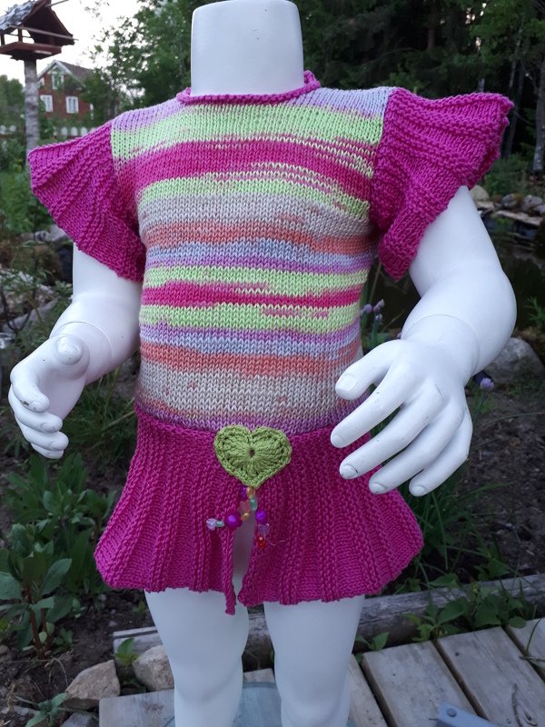 Verspieltes Stricktop in Pastellfarben mit Rüschenärmeln und Herzanhänger auf Schaufensterpuppe