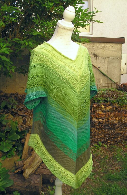 Gestrickte Tunika-Poncho für Damen in Grüntönen mit V-Ausschnitt und dekorativen Lochmustern auf einer Schneiderpuppe.