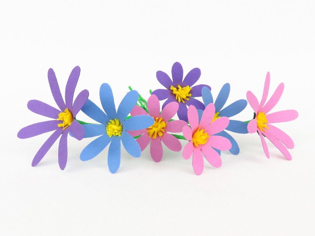 Reihe von sieben Papierblumen in Violett, Hellblau und Pink mit gelben Zentren.