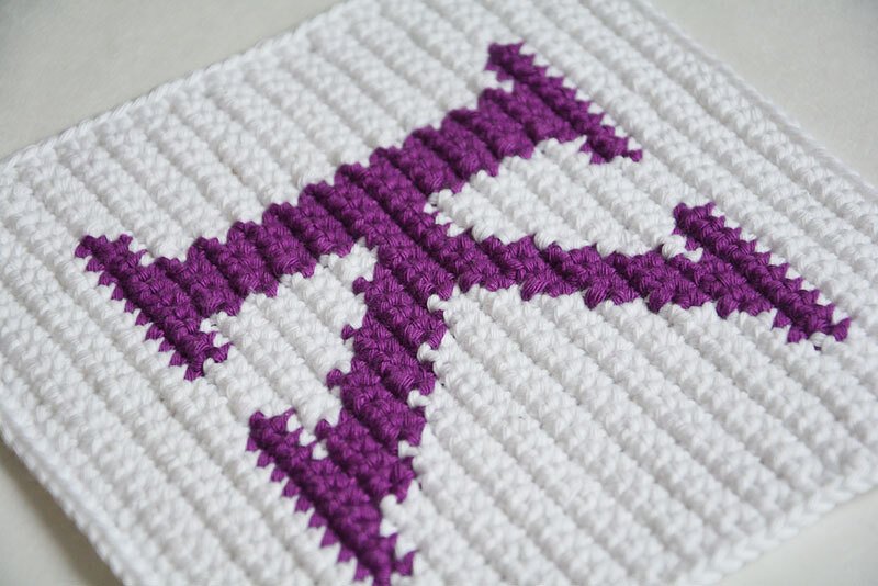 White crocheted square potholder with purple letter F