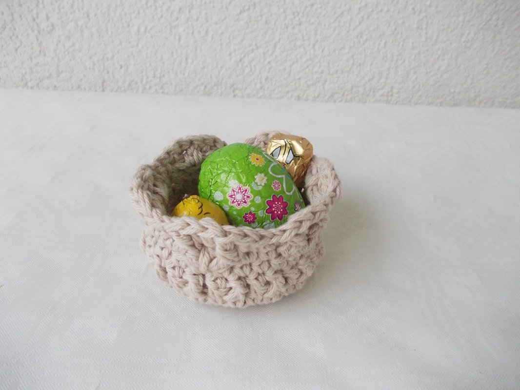 Kleines, schnell gehäkeltes Utensilo aus dickem Garn in Naturfarbe, gefüllt mit Schoko-Ostereiern.
