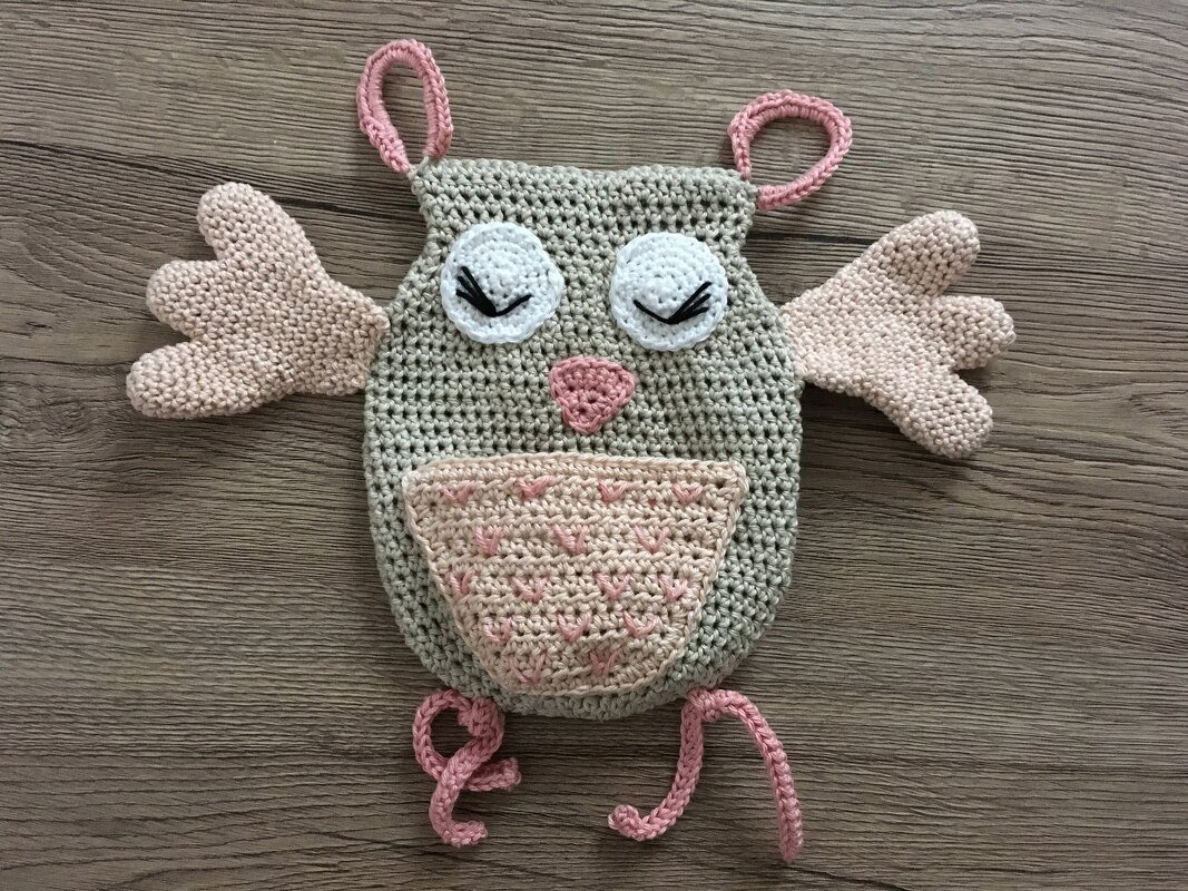 Gehäkeltes Eulen‑Schmusetuch in Grau und Rosa auf Holzhintergrund