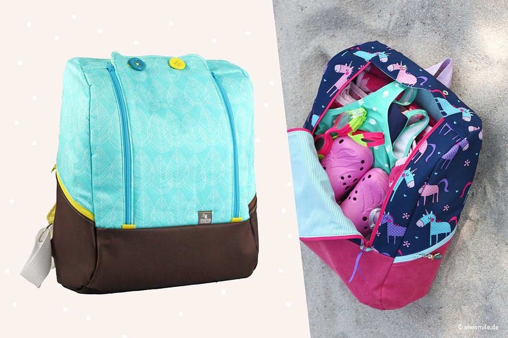 Nahaufnahme von einem türkisen Rucksack mit Blättern und einer offenen Badetasche mit Einhorn-Muster und Inhalt.