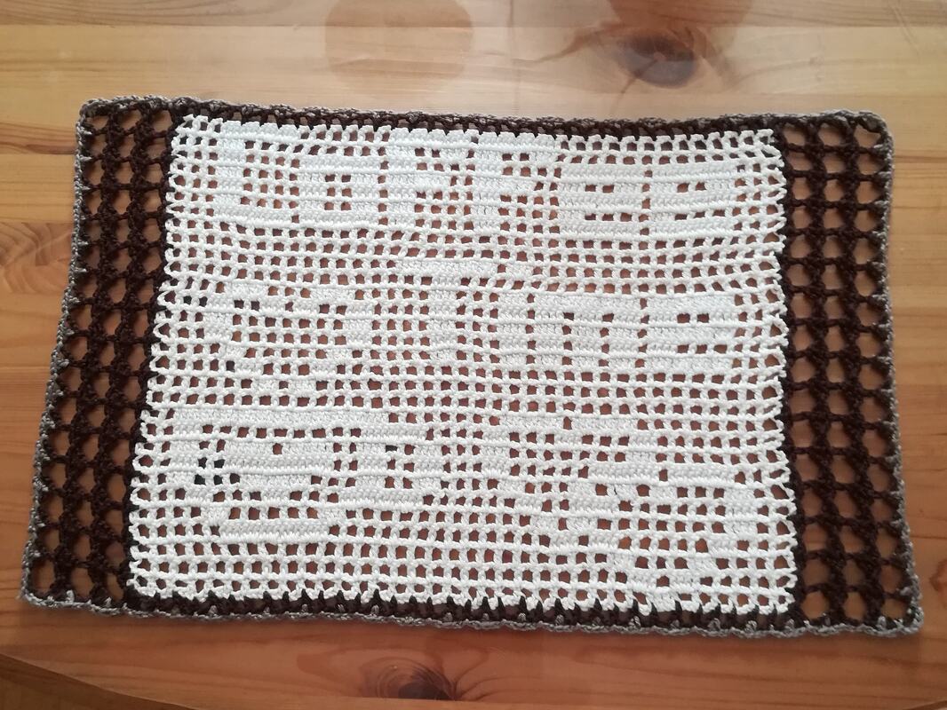 Rechteckiges, gehäkeltes Deckchen mit HOME-Schriftzug, weiß mit dunkelbraunem Rand