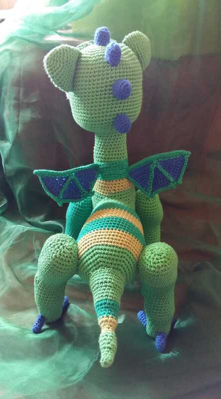 Gehäkelter grüner Amigurumi-Drache, Rückansicht mit blauen Stacheln und gestreiftem Bauch