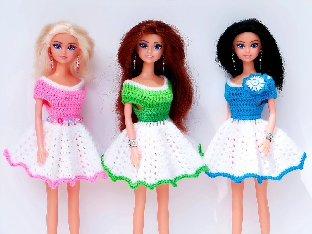 Drei Modepuppen in gehäkelten Kleidern mit weißem Rock und farbigen Oberteilen (rosa, grün, blau)