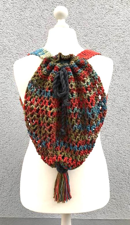 Gehäkelter Beutelrucksack in roten, grünen und blauen Tönen mit Kordelzug und Quaste auf einer Schaufensterpuppe