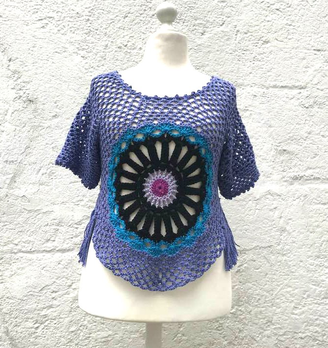 Lila gehäkeltes Damen-Top mit rundem Mandala-Motiv in Schwarz, Türkis, Lila und Pink, kurzen Ärmeln und seitlichen Fransen.