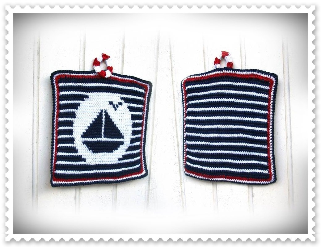 Zwei gehäkelte Topflappen in Dunkelblau, Weiß und Rot; vorn Segelboot-Motiv im weißen Kreis, hinten gestreifte Rückseite, mit gedrehter Aufhängeschlaufe