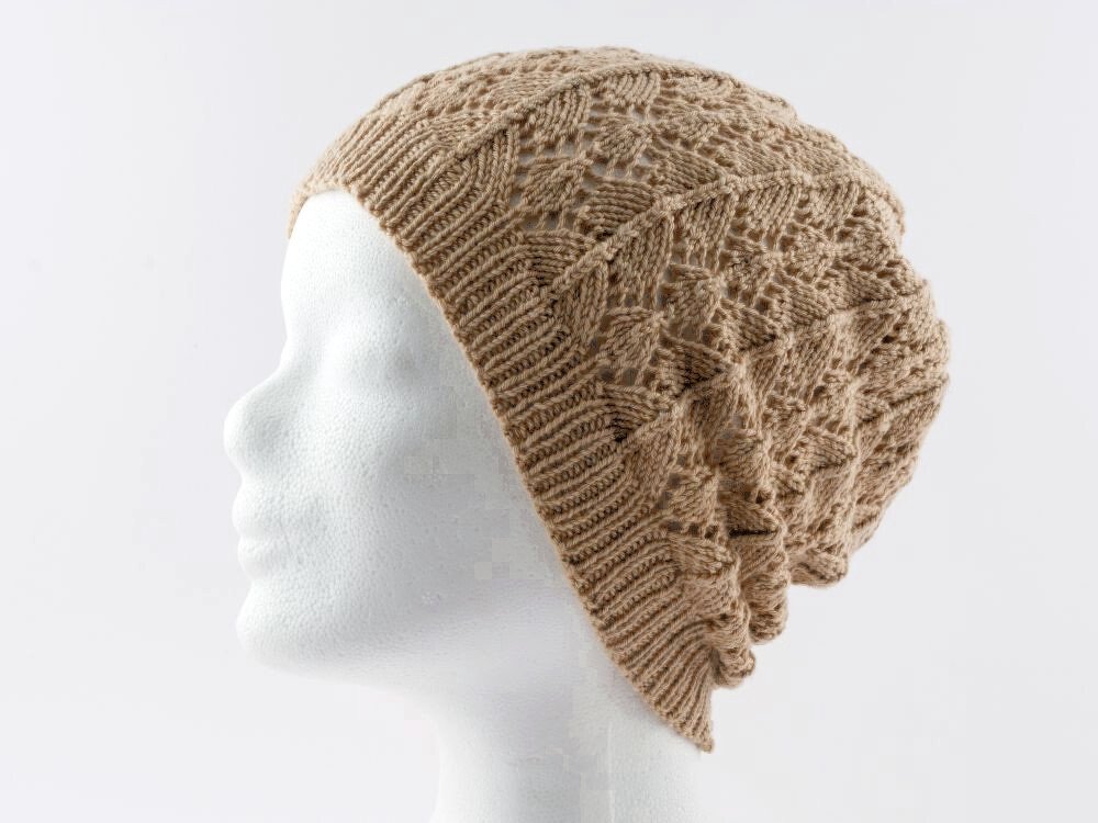 Beige gestrickte Slouchy-Mütze mit Ajour-Lochmuster auf weißem Schaufensterkopf, Seitenansicht