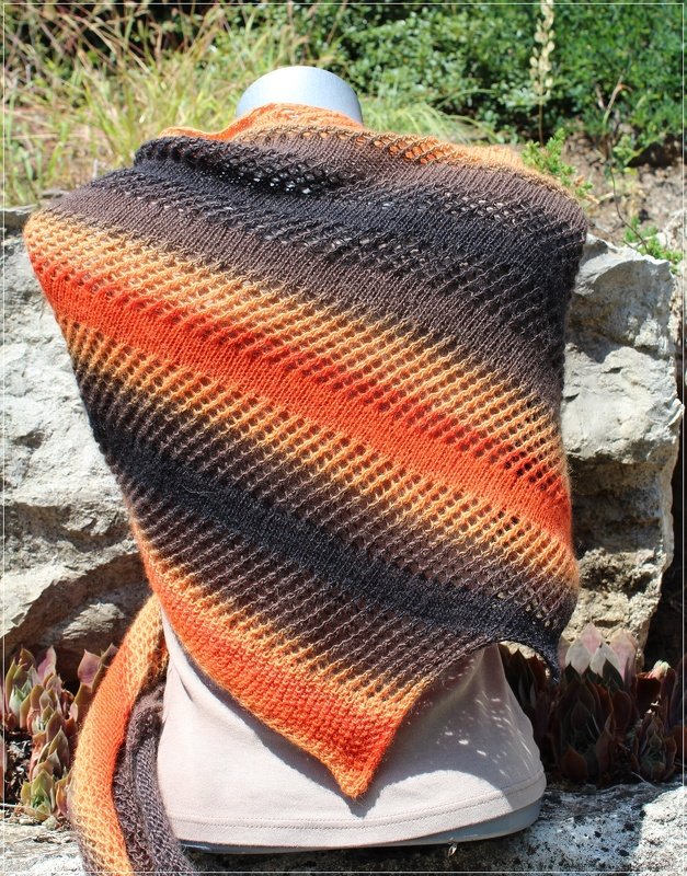 Dreieckstuch in Orange und Braun mit diagonalen Ajourstreifen auf einer Büste vor Felsen