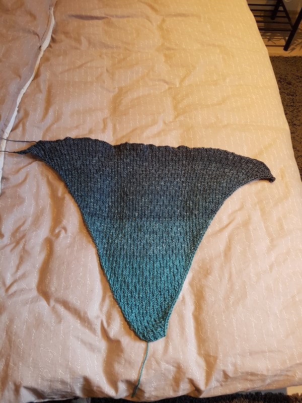 Gestricktes Dreieckstuch mit Farbverlauf von Grau zu Türkis auf hellem Untergrund ausgebreitet