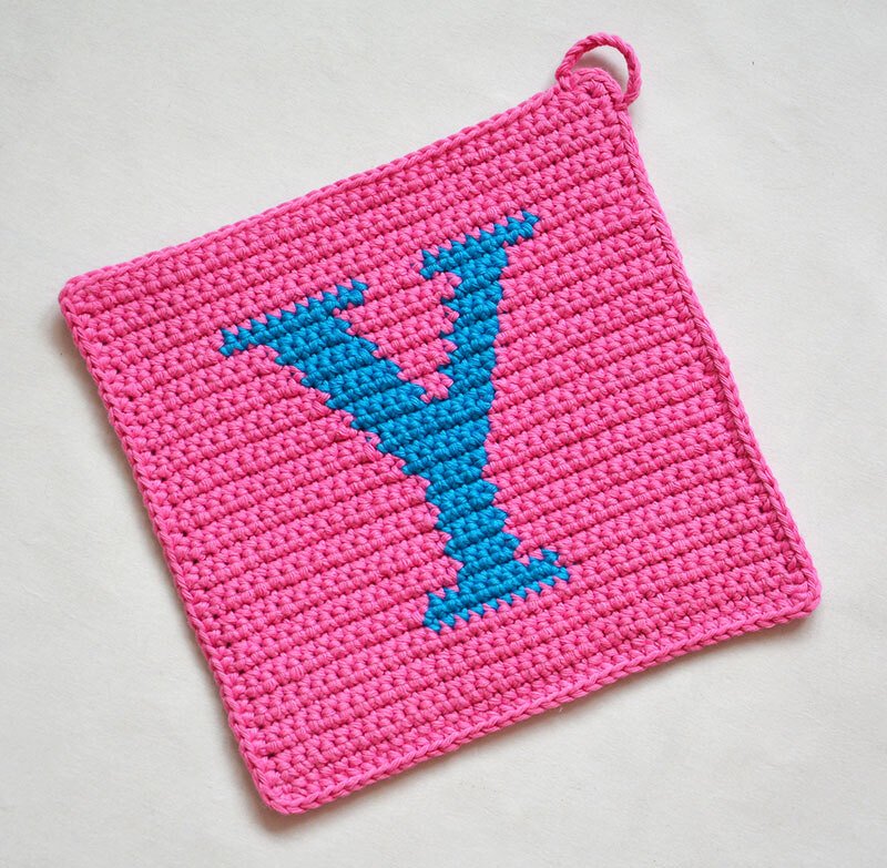 Square pink crocheted potholder with blue letter Y and corner hanging loop