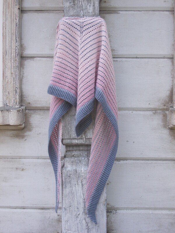 Gestricktes Dreieckstuch in Rosa mit grauem Rippenrand, hängend an einer verwitterten Holzlatte